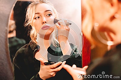 Young woman contouring her face applying make up with makeup brush Stock Photo