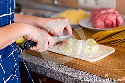 Young woman is cooking and chopping onions Stock Photo