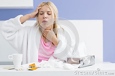 Young woman coughing while suffering from headache and cold in kitchen Stock Photo