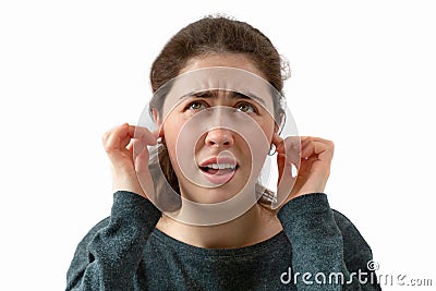 A young woman covers her ears from the noise. Emotion of discontent and irritation on the face. Isolated Stock Photo