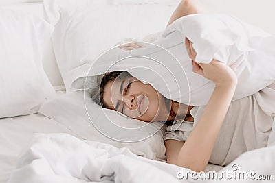 Young woman covers her ears with a pillow Stock Photo