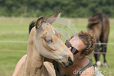 Young woman cuddling with her best friend, falcon color stallion foal, share a loving moment Stock Photo