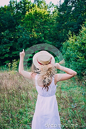 Young woman with curly hair in a hat. Slender girl in a hat with her back turned. Photo of a girl from the back Stock Photo