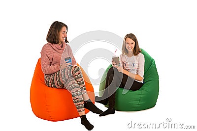 Young woman and cute girl sitting on beanbag chairs and drinking Stock Photo