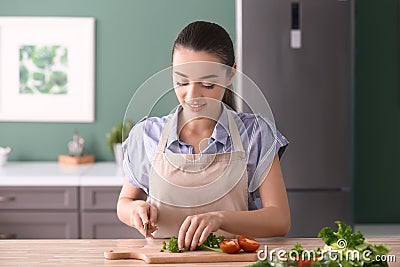 Young woman cutting parsley for salad in kitchen Stock Photo