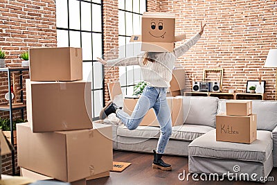 Young woman dancing with funny cardboard box on head at new home Stock Photo