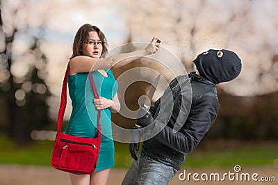 Young woman is defending with pepper spray against armed thief. Stock Photo