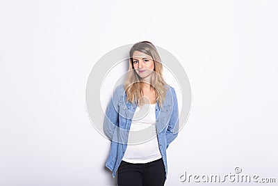 Young Woman in Denim Shirt and Jeans, Leaning Against Gray Wall Background Stock Photo