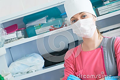Young woman doctor anesthesiologist dressed in mask, glasses and hat ready for surgery and looking into the camera Stock Photo