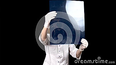A young woman doctor checks the results of an MRI scan of a spine. A woman examines an MRI image then shows a thumb down Stock Photo