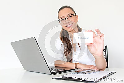 A young woman doctor with a laptop in her office holds a business card Stock Photo