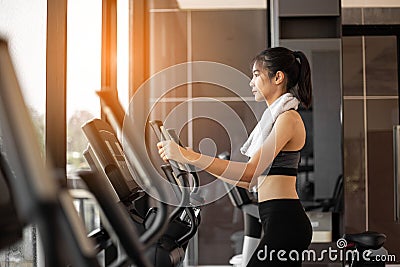 Young woman doing exercise cardio on elliptical trainer at gym Stock Photo