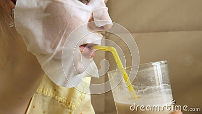 Young woman doing facial mask mask with cleansing mask, clicks on couch with smartphone at home Stock Photo