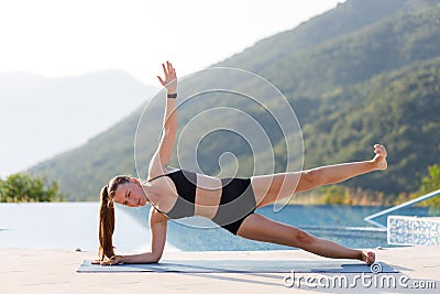 Young woman doing outdoor yoga training in the morning in mountains Stock Photo