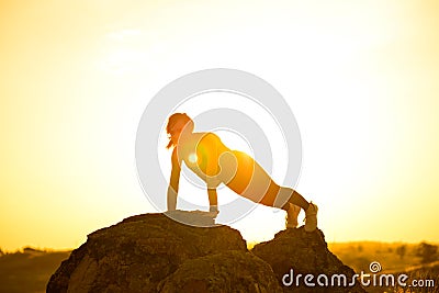 Young Woman Doing Push-ups in the Mountains. Workout Exercise at Sunset. Sport and Healthy Active Lifesyle Concept Stock Photo