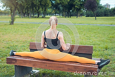 young woman doing split on a bench in the park Stock Photo