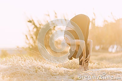 Young woman doing stretching yoga exercise at golden sunset outdoors Stock Photo