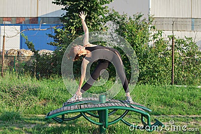 young woman doing triangle yoga pose outdoors Stock Photo