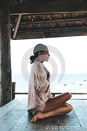 Young woman doing yoga in the wooden gazebo at the beach Stock Photo