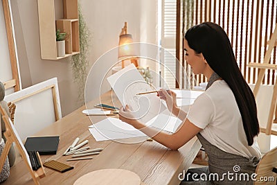 Young woman drawing female portrait at table indoors Stock Photo