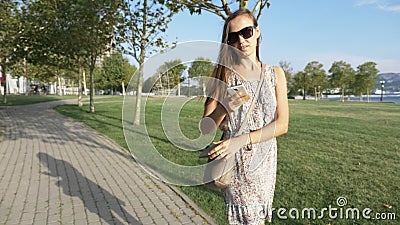 Young woman in dress pulls out from the handbag smart phone and starts talks stock video footage Young woman in dress pulls out from the handbag smart phone and starts talks stock video footage