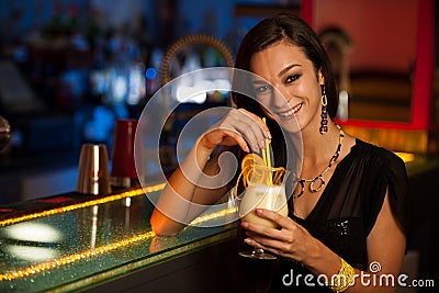 Young woman drinks a cocktail in night club Stock Photo