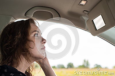 A young woman drives a car and straightens her hair Stock Photo