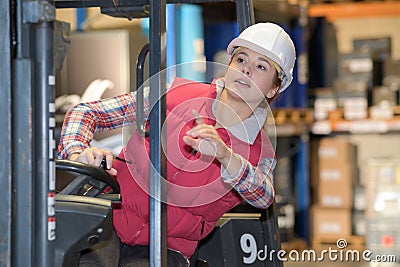 Young woman driving reach truck in warehouse Stock Photo