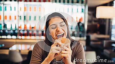 Young woman eating fatty hamburger.Craving fast food.Enjoying guilty pleasure,eating junk food.Satisfied expression.Breaking diet Stock Photo