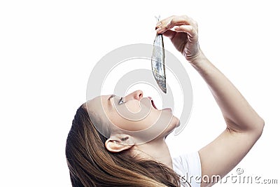 A young woman eats a small raw fish. Health, vitamins and natural products. Isolated on white background. Close-up. Profile view Stock Photo