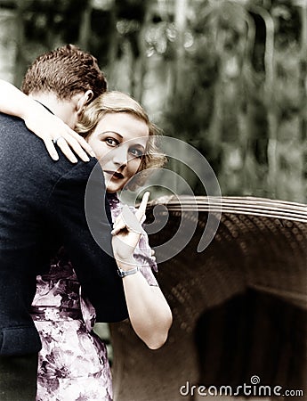 Young woman embracing a man and pointing towards an information board Stock Photo