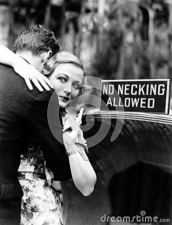 Young woman embracing a man and pointing towards an information board Stock Photo