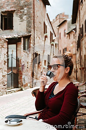 Young woman enjoying coffee in in a cafe in medieval town in Italy Stock Photo