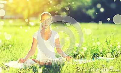 young woman enjoying meditation and yoga on green grass in summer on nature Stock Photo