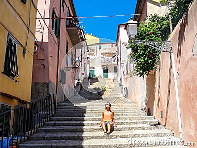 Young woman enjoying the sun in an alley of a small rural medieval village Stock Photo