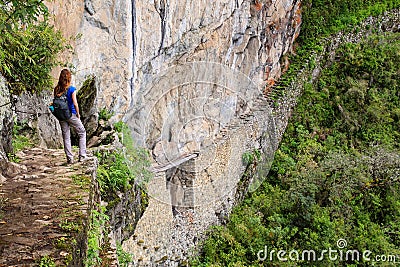 Young woman enjoying the view of Inca Bridge and cliff path near Stock Photo