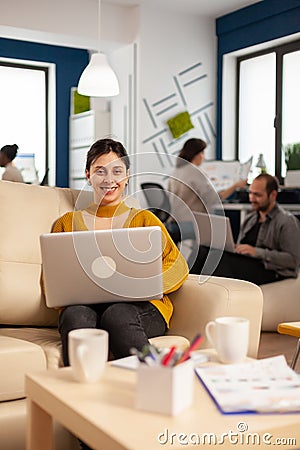 Young woman entrepreneur sitting on couch in middle of business start up office Stock Photo