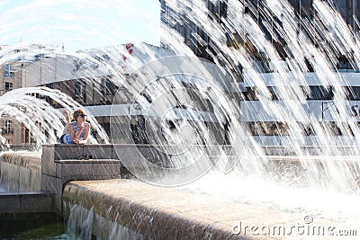 The young woman escaping heat wave in city fountain Stock Photo