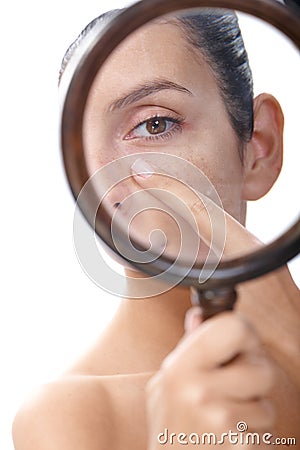 Young woman examining skin with magnifier Stock Photo