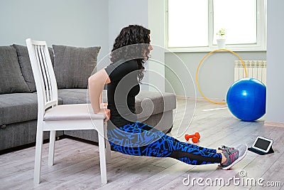 Young woman exercise at home. Sporty healthy lifestyle. Woman using a chair while doing workout Stock Photo