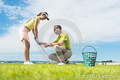 Young woman exercising the golf swing helped by her instructor Stock Photo
