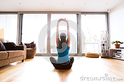 Young woman exercising at home, stretching arms. Stock Photo