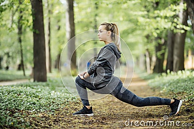 Young woman exercising at park during sunset. Beautiful athletic woman doing her stretches in the park. Sporty woman stretching af Stock Photo