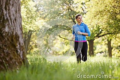 Young Woman Exercising Running Through Countryside Field Stock Photo