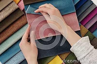 Young woman with fabric samples for curtains at table. Multiple color fabric texture samples selection fabrics for interior Stock Photo