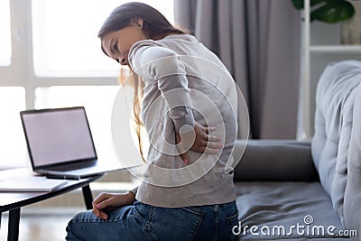 Young woman feeling backpain after sedentary computer work at home Stock Photo