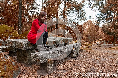 Young woman feeling depressed sitting on a stone table Stock Photo