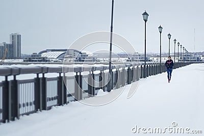 Young woman fitness model running at snow winter park, pink sneakers - wide angle Stock Photo