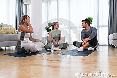 Young woman fitness and yoga instructor helping couple in their home for workout exercises. Female coach working with clients Stock Photo