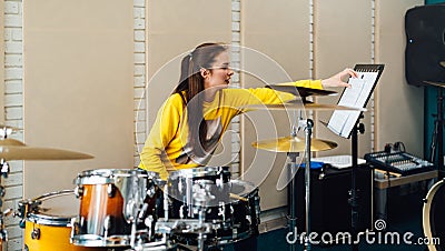 Young woman flipping notes for drumming. Lesson at the drum music school. Stock Photo